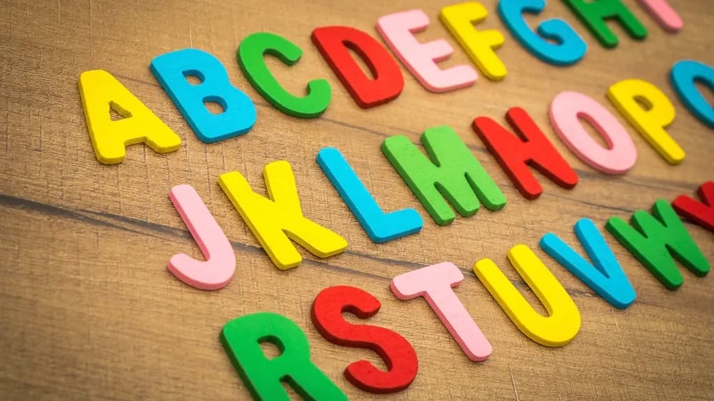 Letras magnéticas de colores colocadas en filas sobre una mesa de madera