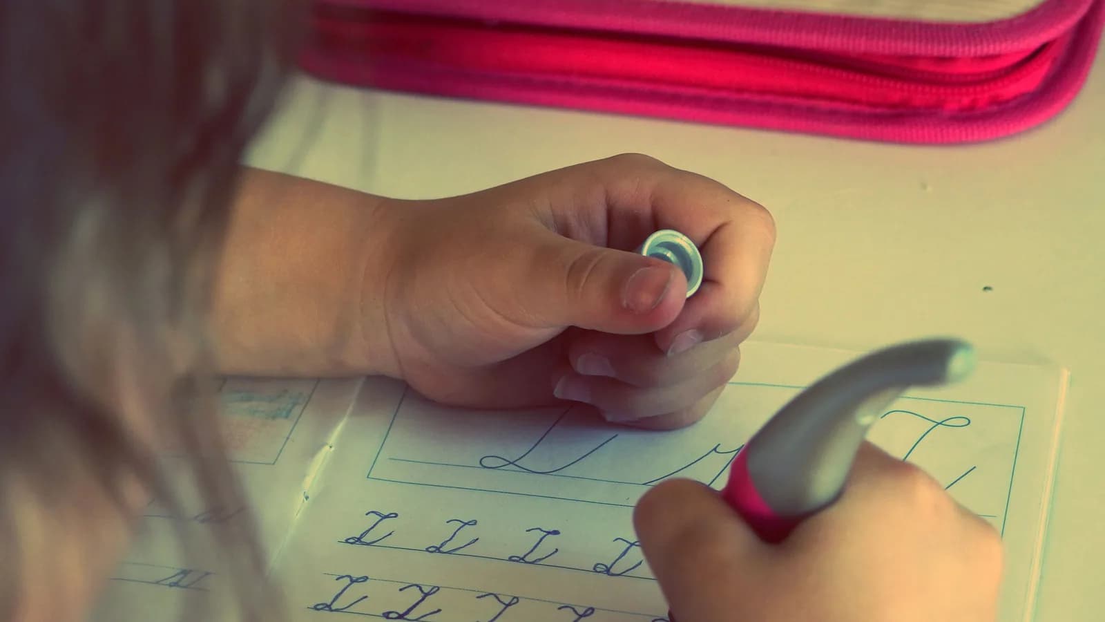 Mano de una niña repasando el trazo a lápiz sobre una ficha pautada