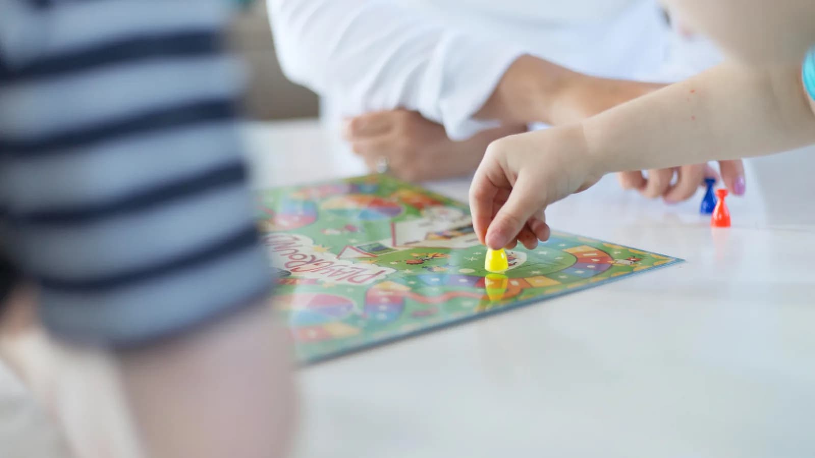 Manos de un niño colocando una ficha sobre el tablero de un juego de mesa